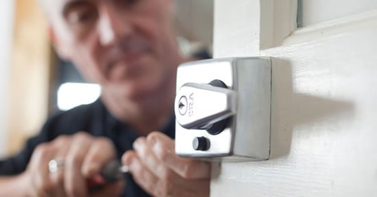 person replacing a lock on a door